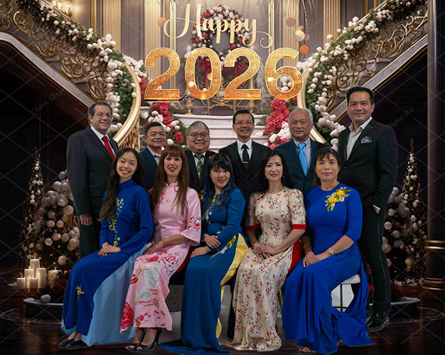 Two rows of people, one seated and one standing, are superimposed over a background featuring a staircase and the words "Happy 2026."